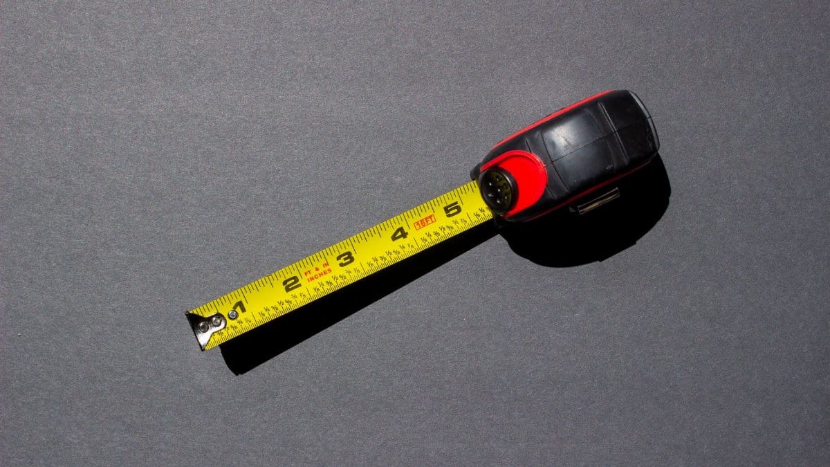 Close-up of a yellow measuring tape on a dark surface under bright lighting.