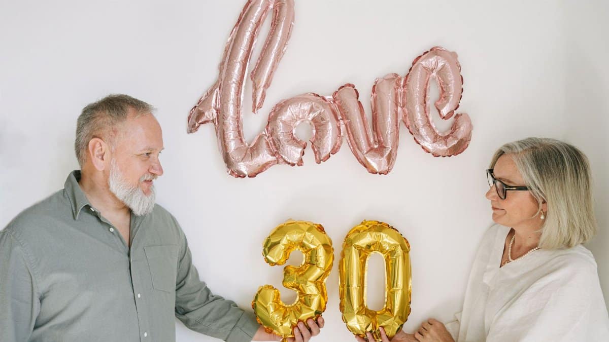 Elderly couple celebrating 30th anniversary with love-themed balloons.