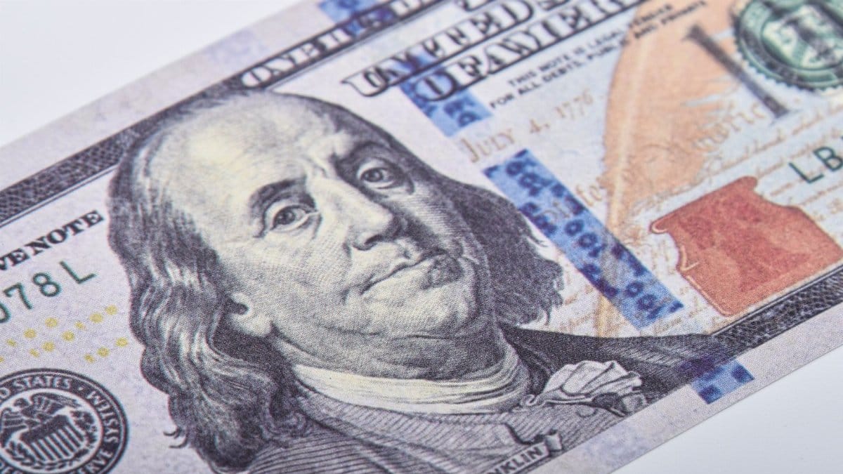Macro shot of a US hundred dollar bill featuring Benjamin Franklin on a white surface.