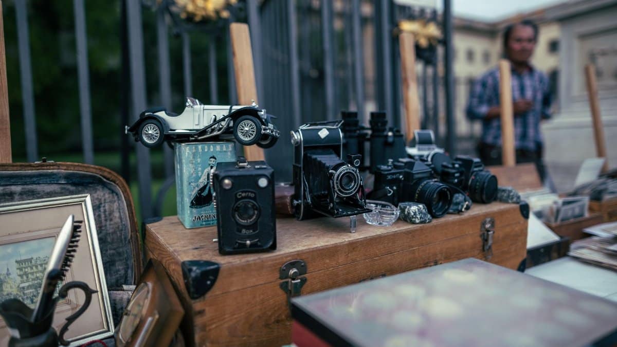 An assortment of vintage cameras and collectibles displayed at an outdoor flea market.