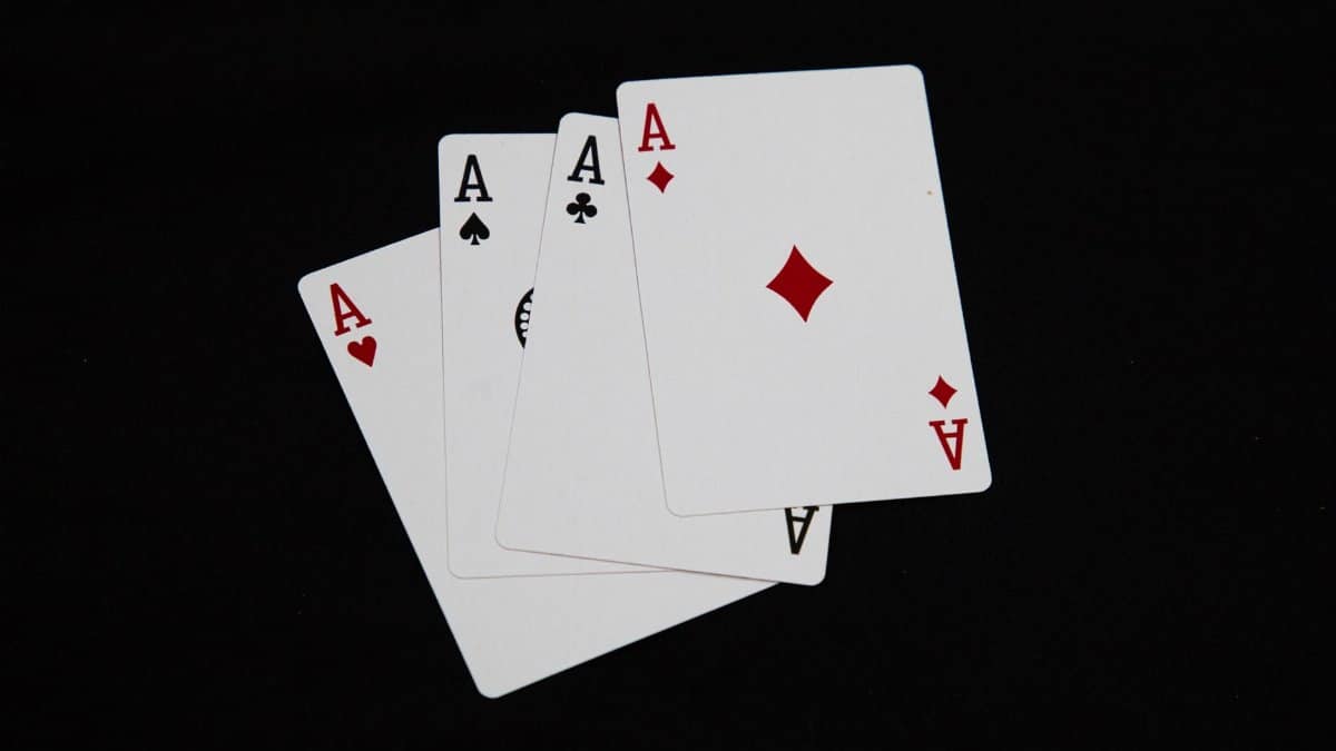 A set of four aces from a deck of playing cards arranged on a black background.
