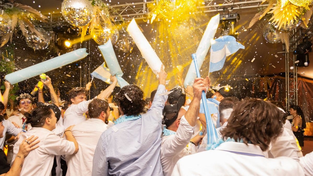 Joyous indoor party scene with people celebrating under disco balls and confetti in Mendoza, Argentina.