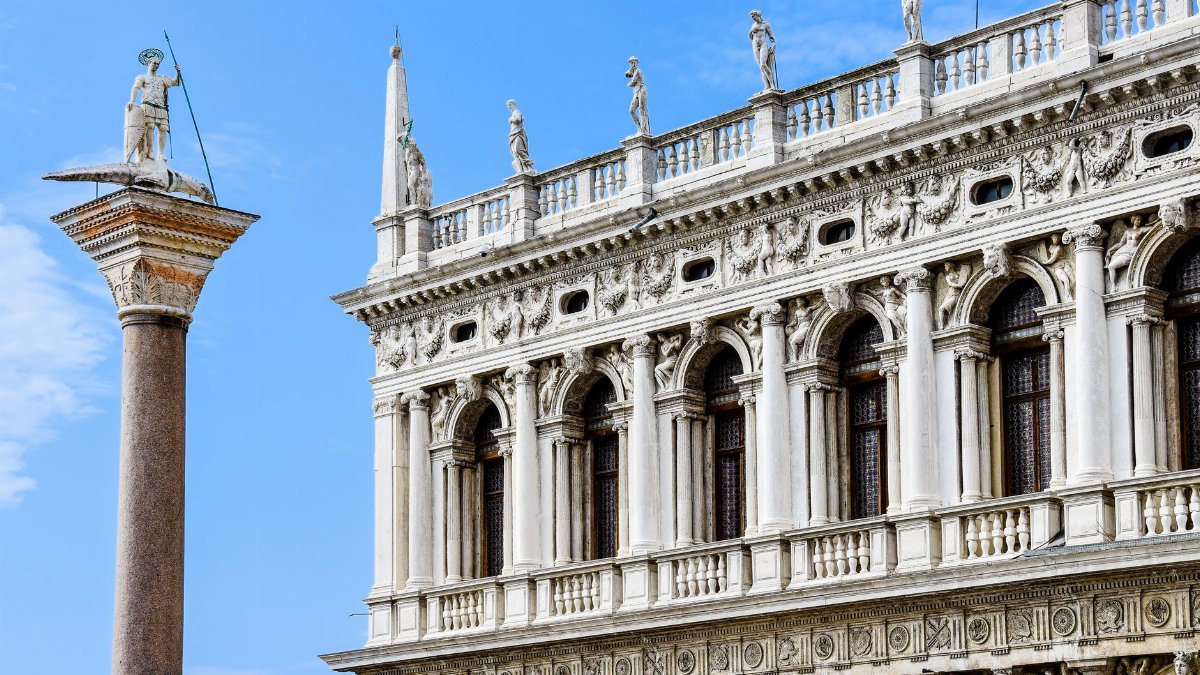 Stunning view of Biblioteca Marciana and column in Venice's Piazza San Marco under a blue sky.