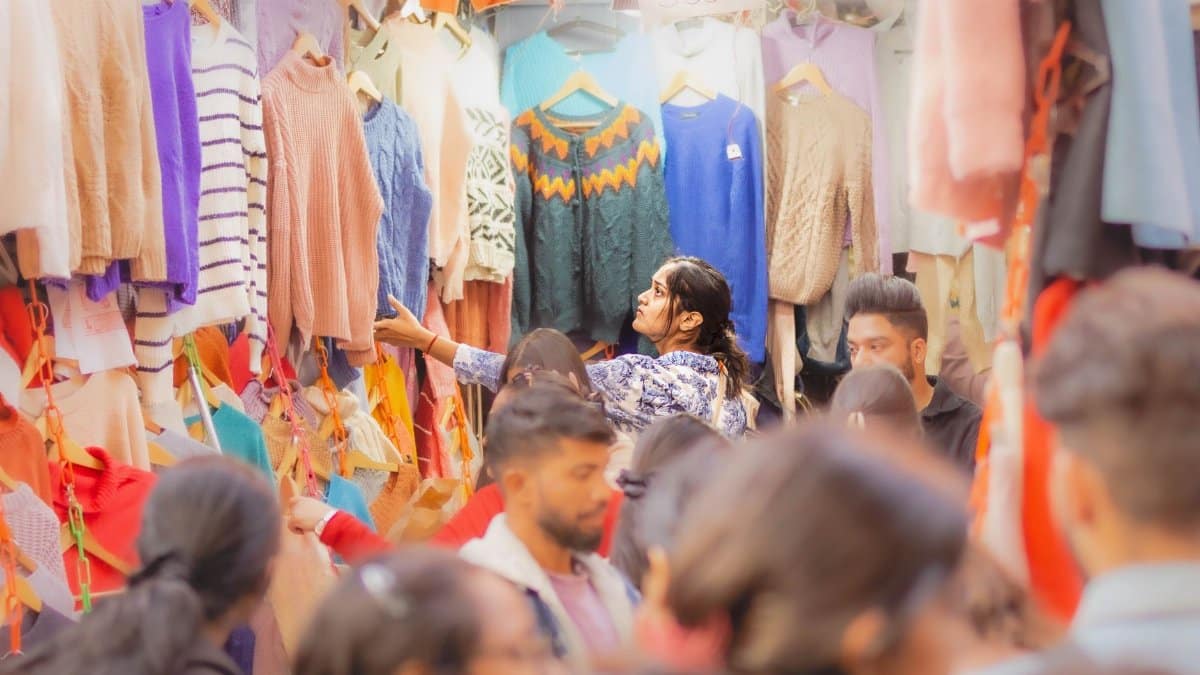 Vibrant crowd shopping for clothes at a bustling New Delhi bazaar.