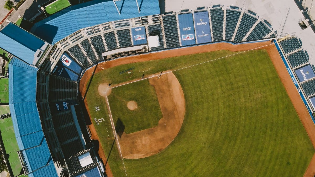 Top-down aerial shot of an empty baseball stadium with blue seating and green field.