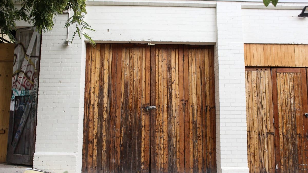 Rustic wooden garage doors set against a white brick wall, showcasing texture and urban style.