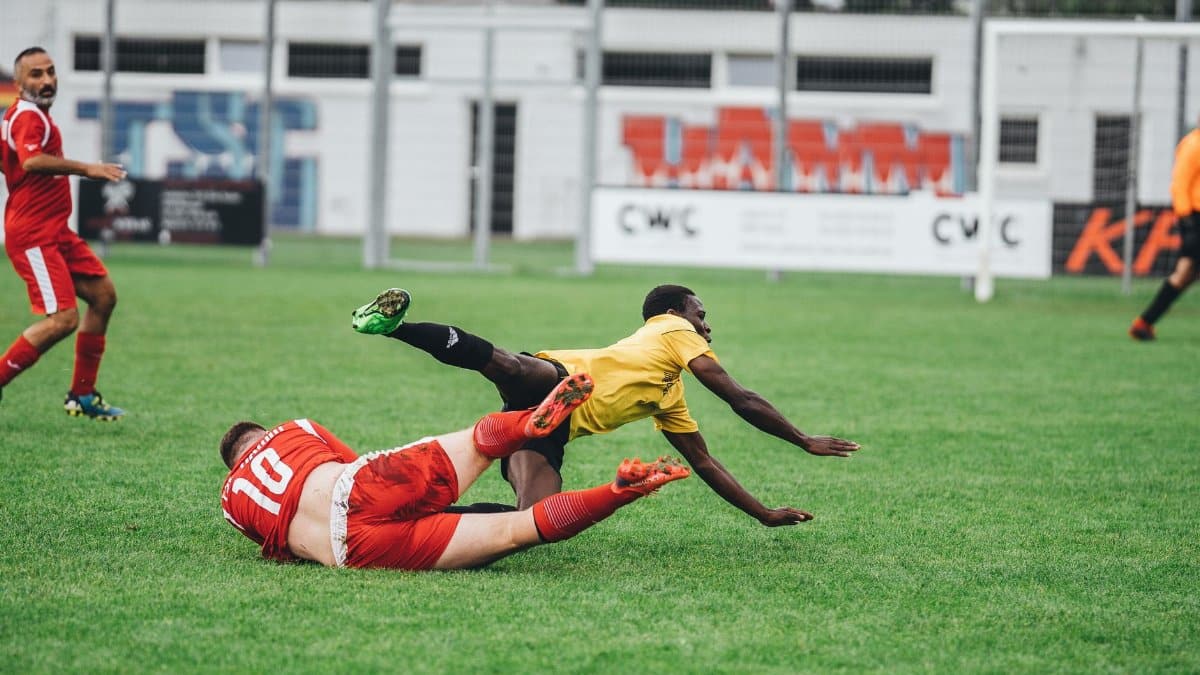Intense soccer match showing players in motion on a grassy field during the day.