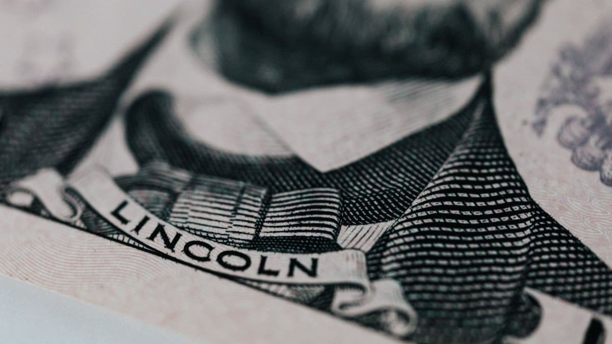 Crop of five dollar banknote with president Lincoln wearing costume on table