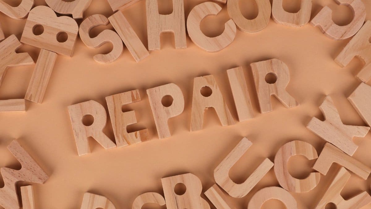 Top view of wooden letters arranged to spell 'REPAIR' on a beige background, perfect for DIY themes.