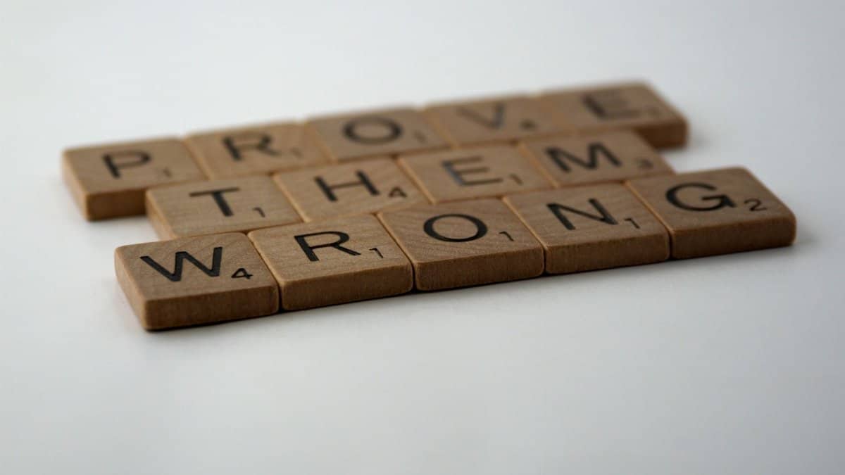 Scrabble tiles spelling 'Prove Them Wrong' on a white background, conveying motivation.