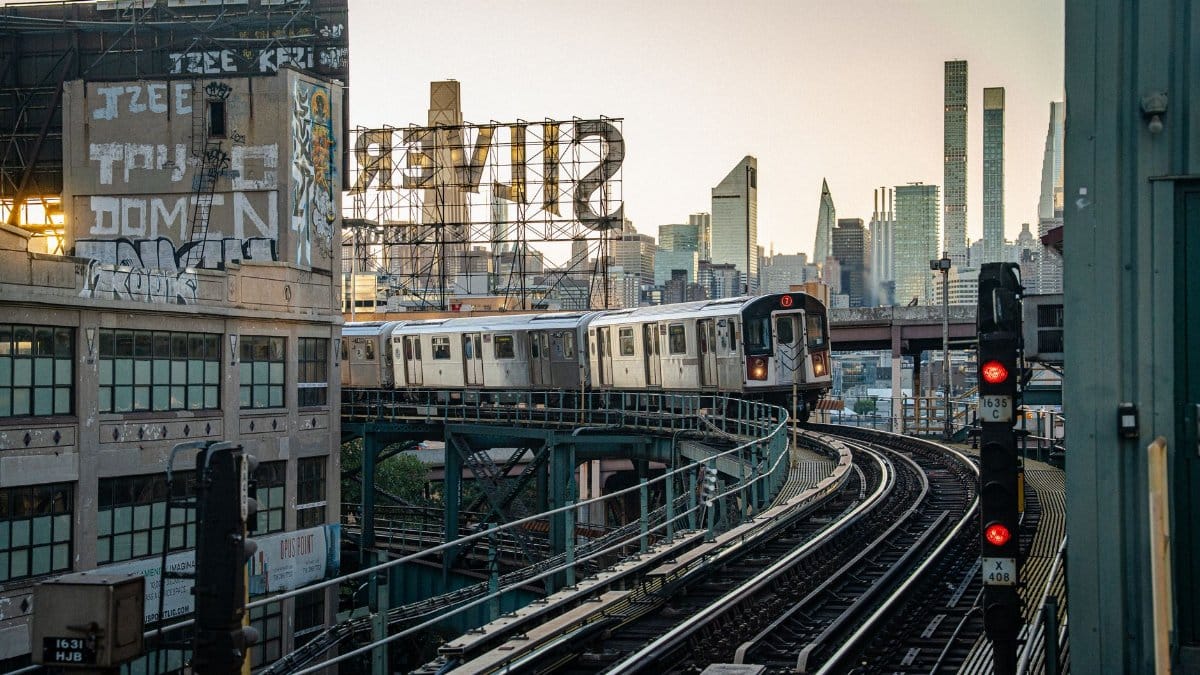 Capture of NYC subway in motion with city skyline backdrop during golden hour.