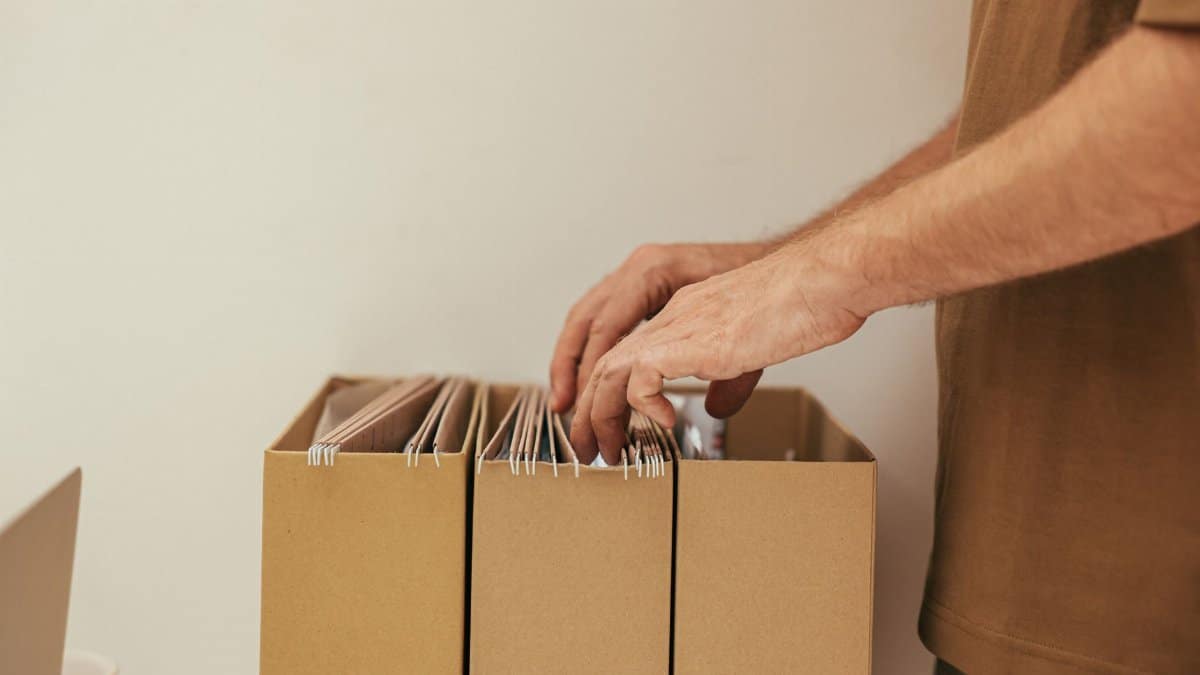 Close-up of a person organizing files in cardboard boxes, ideal for business and office themes.