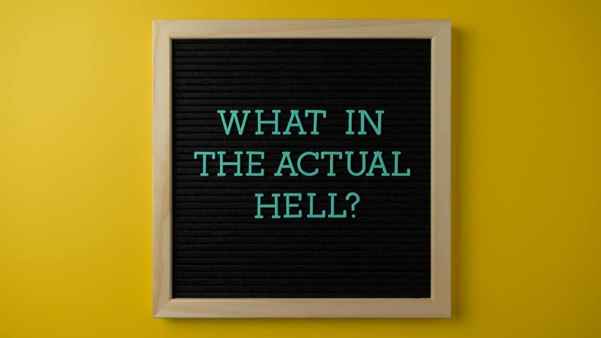 Letter board with humorous quote 'What in the actual hell?' on a vibrant yellow backdrop.