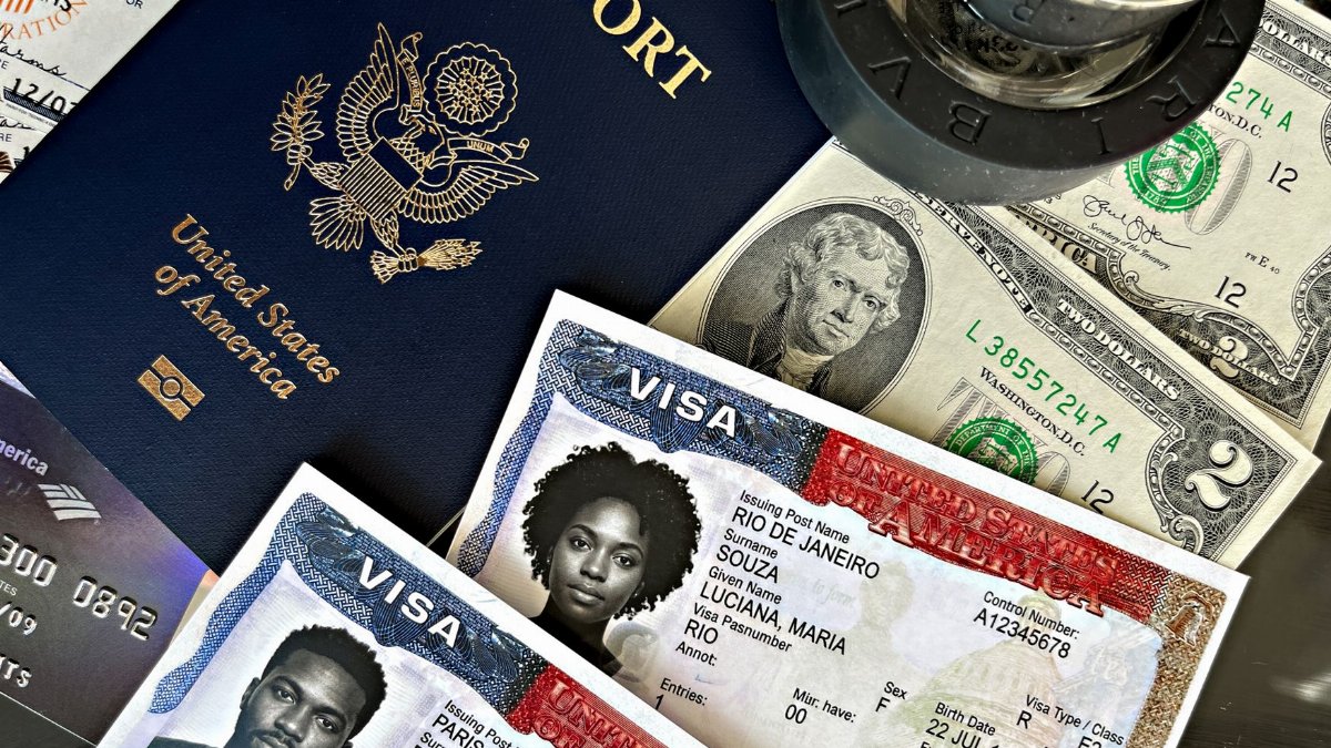 Close-up of a US passport, visa documents, currency, and stamps.