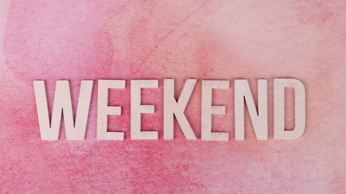 Creative display of the word 'Weekend' in wooden letters on a textured pink background.