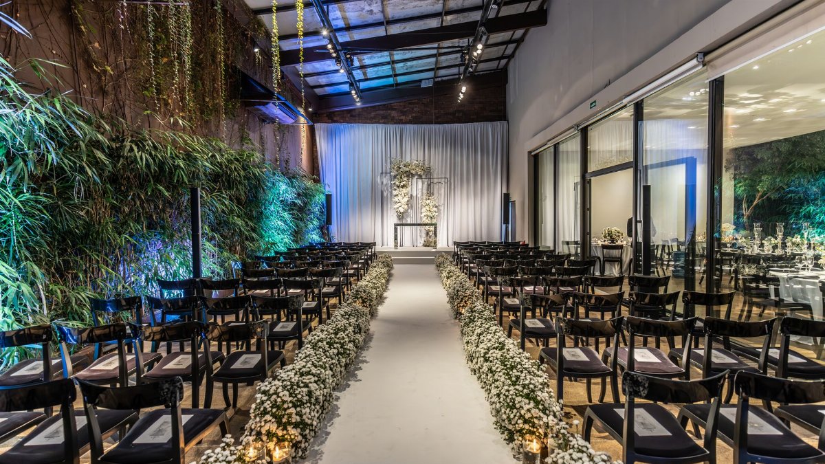 Beautifully decorated wedding venue with aisle, chairs and floral arrangements indoors.