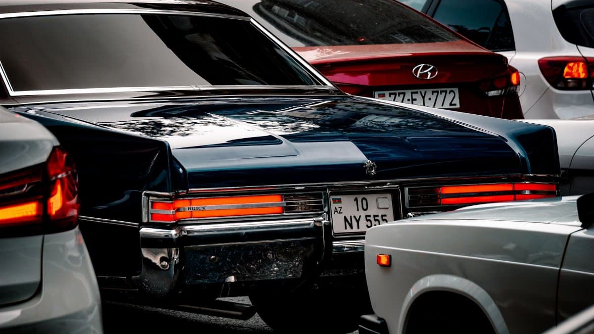 A classic Buick surrounded by modern cars in a bustling city traffic context.