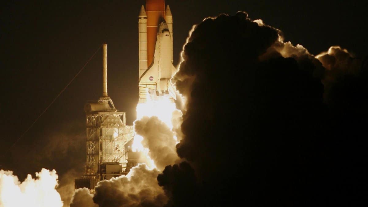 Dramatic capture of a space shuttle launching into the night sky, shrouded in smoke.