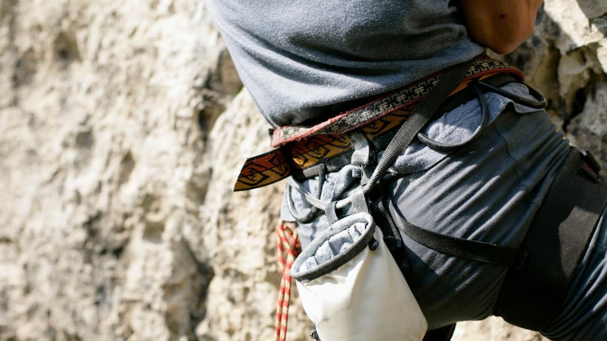 Detailed shot of rock climbing gear including harness and chalk bag during an outdoor climb.