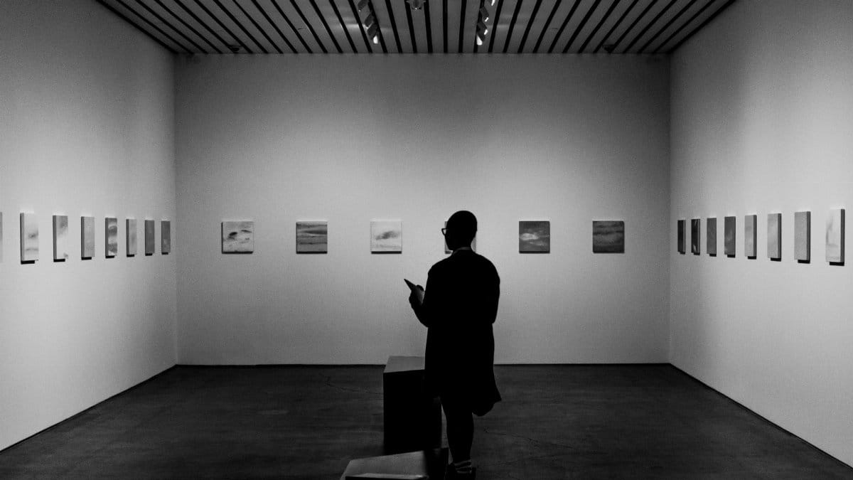 A person observes artwork in a monochrome art gallery exhibition, Cleveland.