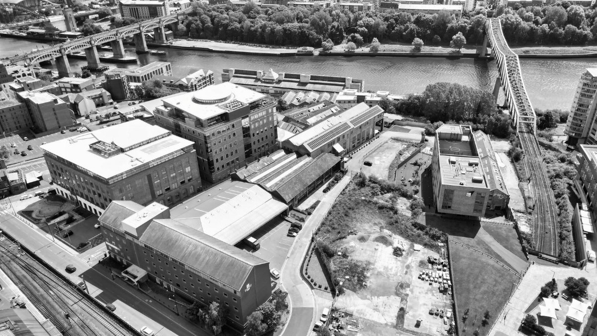 Black and white aerial view of Newcastle's iconic bridges and cityscape along the River Tyne.
