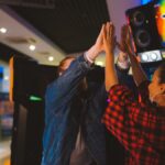 Energetic couple having fun at an arcade, sharing a high five and laughter.