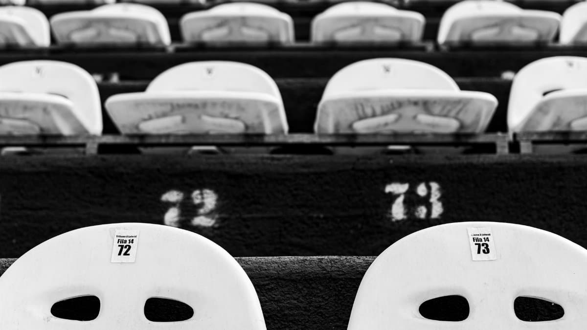 Monochrome image displaying numbered empty stadium seats, creating a repetitive pattern.