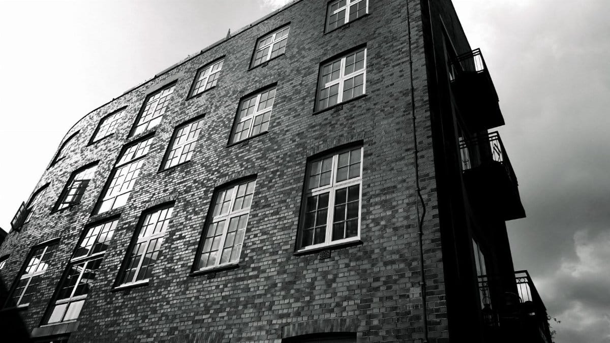 Low angle monochrome view of a brick building emphasizing geometry and contrast.