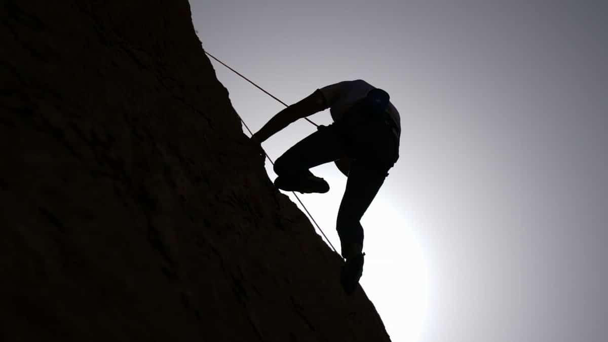 Dramatic silhouette of a climber scaling a rock face at sunset in Damascus, Syria.