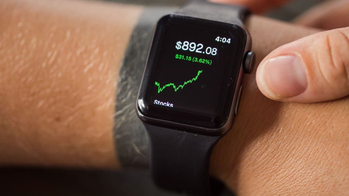 Close-up of a smartwatch showing stock market trends and financial data.