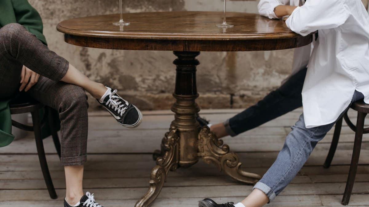 Two people relax with drinks at a rustic table, showcasing casual style and ambiance.