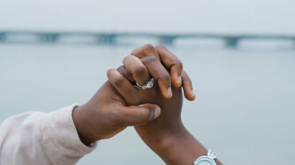 A couple holds hands with engagement ring visible over the bridge in Lagos, Nigeria.