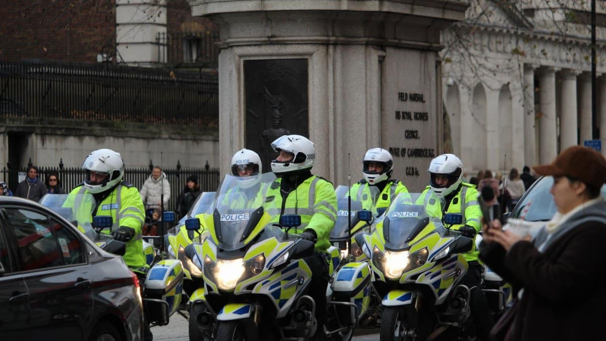 Police officers on motorcycles patrolling an urban intersection with onlookers.