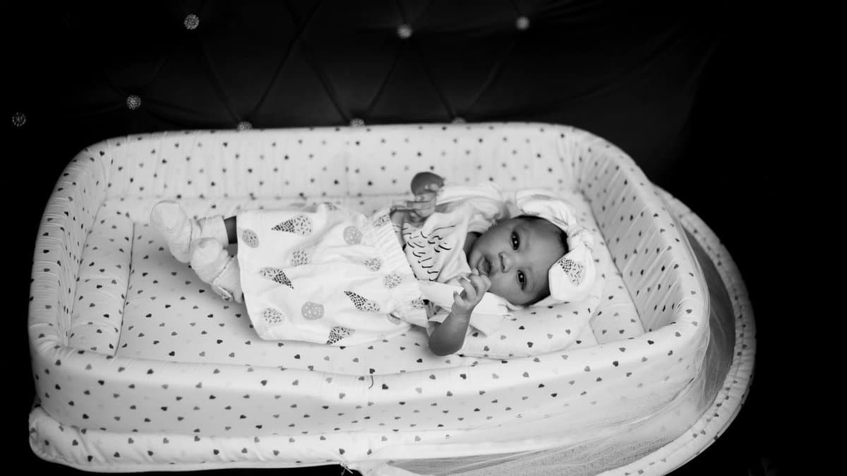 Black and white photo of a newborn baby lying in a comfortable crib.