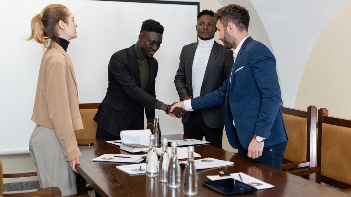 A diverse group of professionals engaged in a business meeting, sealing a deal with a handshake.