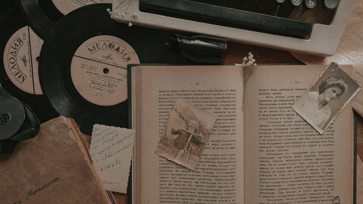 A nostalgic still life featuring a typewriter, vinyl records, and an open book.
