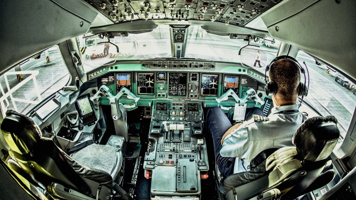 View of an airplane cockpit with a pilot actively managing the controls.
