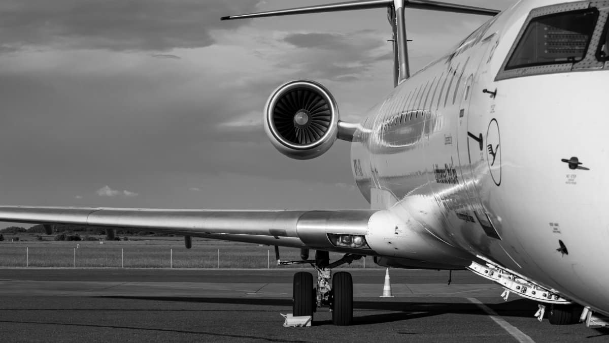 Monochrome photo of a commercial jet airplane taken from the side at an airport.