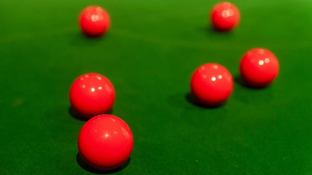 Close-up view of red snooker balls on a green felt table, perfectly arranged for a game.