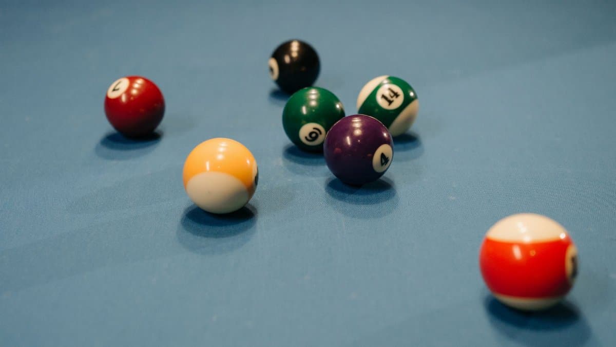 Colorful billiard balls scattered on a blue pool table, capturing a vibrant moment of still life.