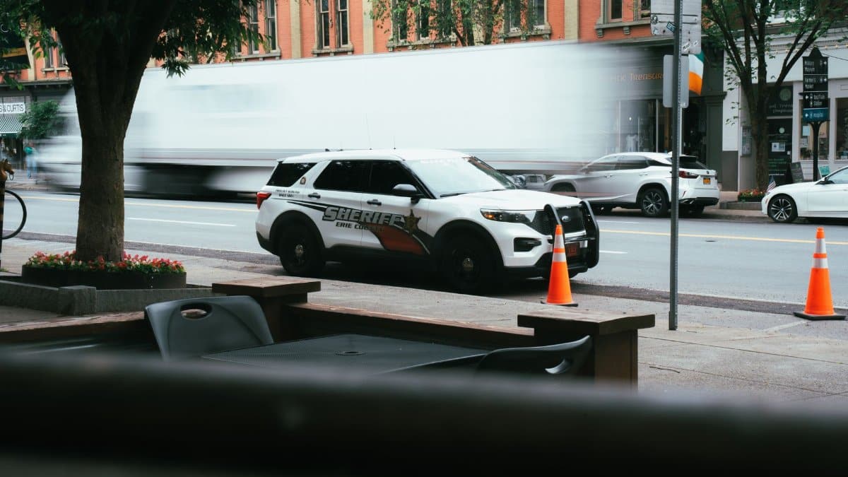 A dynamic urban scene featuring a sheriff police car and blurred traffic in a downtown area.