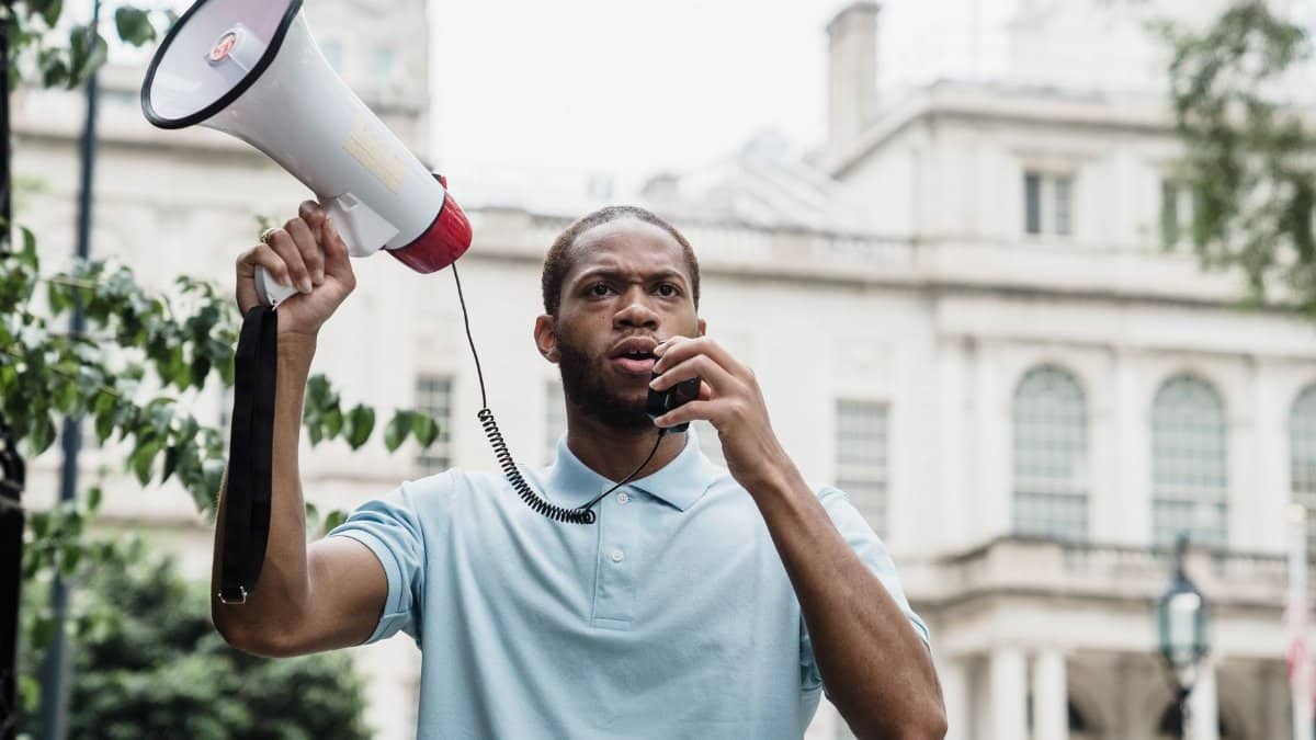 A man passionately speaking through a megaphone during an outdoor protest rally.