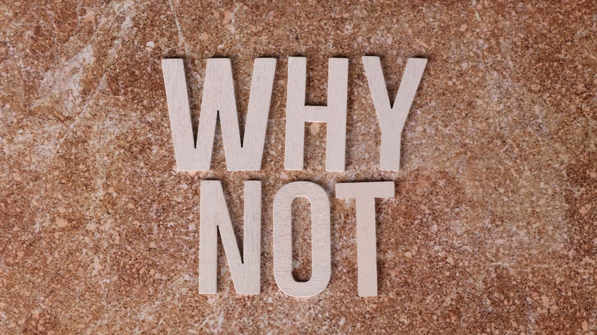 Wooden letters spelling 'WHY NOT' on a textured stone surface background.