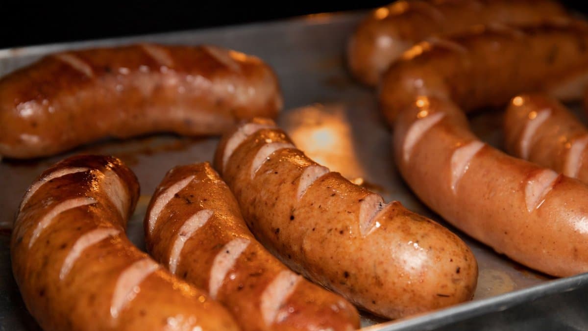 A close-up of juicy grilled sausages on a metal tray, perfect for food lovers.