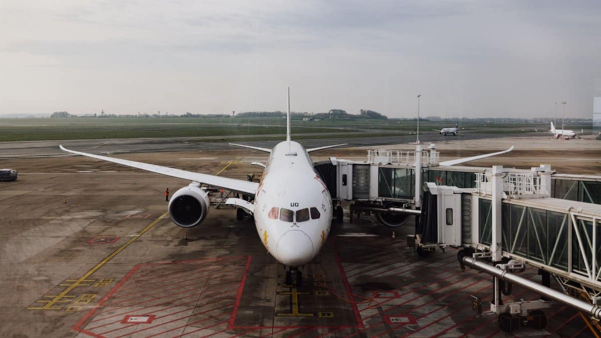 A modern jet airplane docked at an airport terminal gate, ready for boarding on a cloudy day.