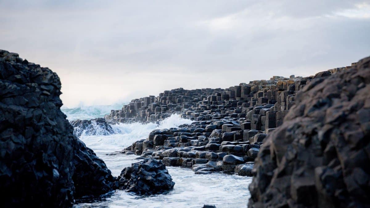 Majestic view of the Giant's Causeway with ocean waves crashing against basalt columns in Northern Ireland.