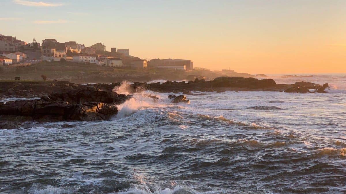 Waves crashing against rocks at sunset in Vila Praia de Âncora, Portugal, creating a scenic coastal view.