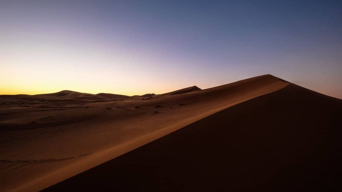 Breathtaking view of sand dunes under a colorful sunset in the Moroccan desert.