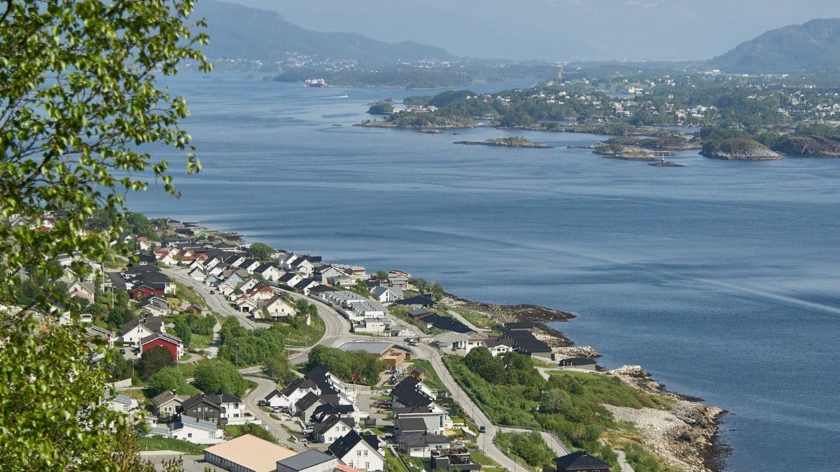 Aerial view of Ålesund, Norway, showcasing its coastal town and islands under a bright summer sky.