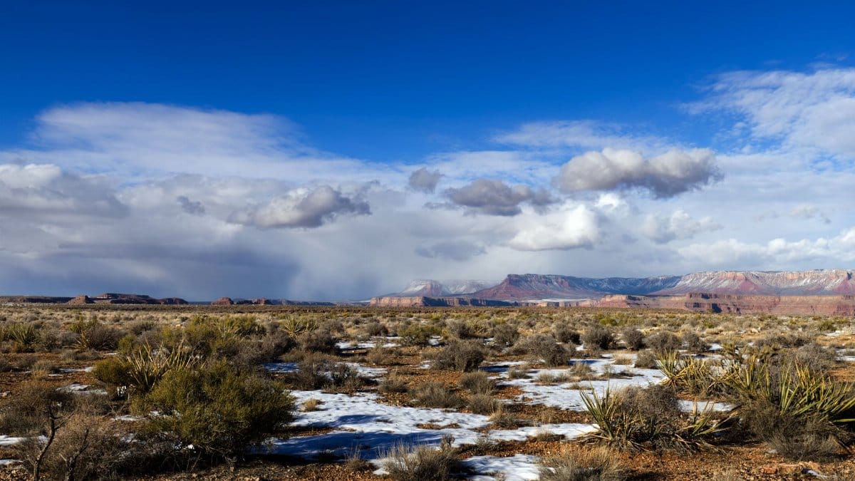 Breathtaking view of Grand Canyon West with touches of snow under a bright blue sky.